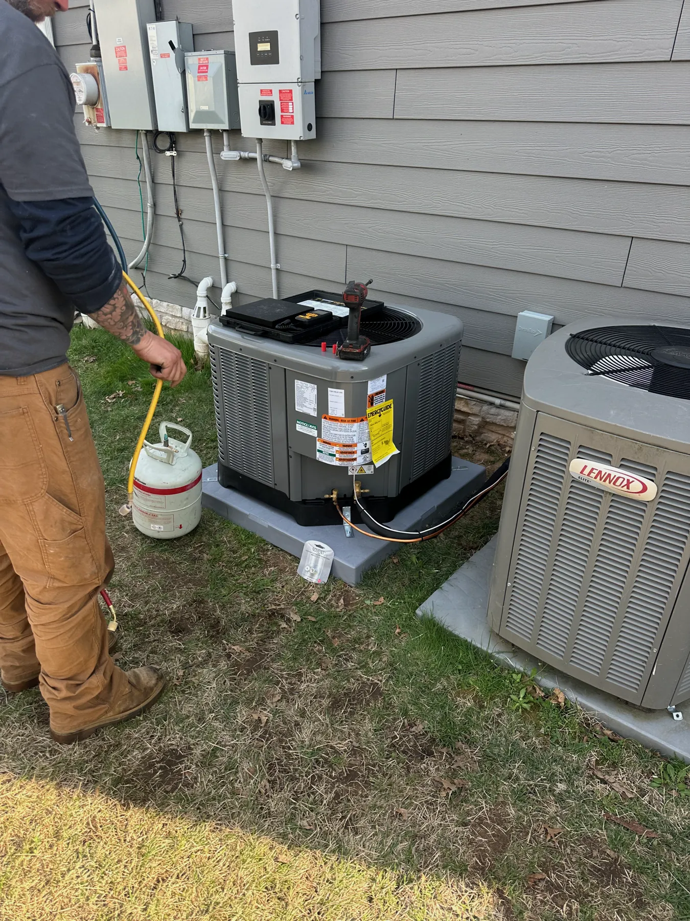 Technician charging residential AC condensers with refrigerant gauges